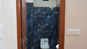 Un baño con inodoro, ducha y un cubo verde.