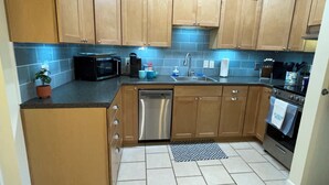 A kitchen with wooden cabinets, a dishwasher, a microwave, a sink, and a stove. - Easy Beach Stay For Families + King Bed + Bikes + Pool! (St. Simons Island)