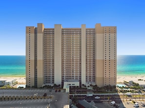 Un hotel moderno de gran altura con varios balcones, piscina y vistas a la playa.