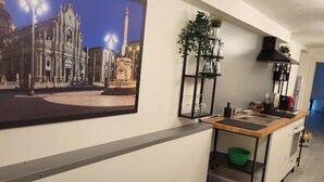 Ett modernt kök med en central köksö, en diskho och en spis. På väggen hänger en inramad tavla som föreställer en historisk byggnad.