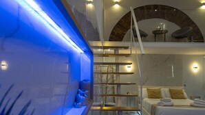 A modern bedroom with a bed, a staircase, and a blue-lit wall. - ARCUM suites è situato nel cuore di Palermo ,non dovrai usare nessun mezzo  (Palermo)