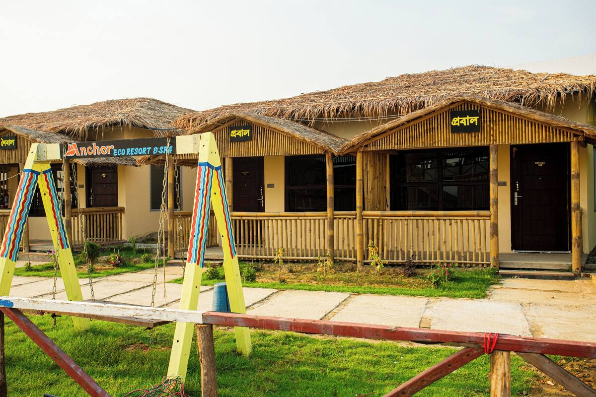A row of thatched-roof huts with a sign reading "Anchor Eco Resort & Spa".