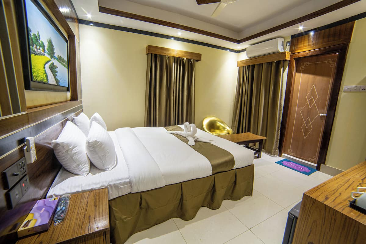A hotel room with a bed, a desk, a chair, and a door.