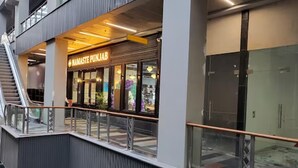 A modern building with a sign reading "NAMASTE PUNJAB" and a glass facade. - Luxury Deluxe Suite by Gt Studios (Greater Noida)