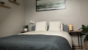 Ein Schlafzimmer mit einem Bett, einem Wandbild und einer Topfpflanze.
