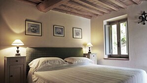 A bedroom with a bed, two bedside tables, a window, and three framed pictures on the wall.