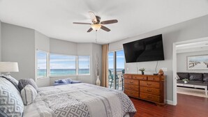 Une chambre avec un lit, une commode, une télévision et un balcon donnant sur l’océan.