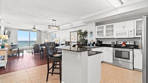 Une cuisine moderne avec des meubles blancs, un îlot central et un coin repas offrant une vue agréable.