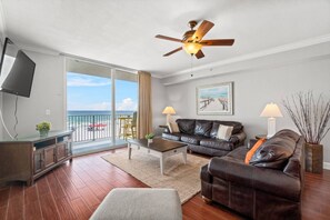 Relax in this stylish living room with a large, open-plan layout and sliding glass door leading to a balcony with ocean views.