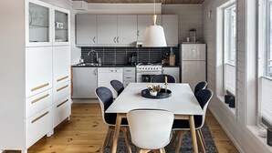 A modern kitchen with white cabinets, a dining table with chairs, and a hanging light fixture. - Awesome apartment in Tjørhom (Tjørhom)