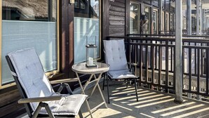 A balcony with two chairs and a small table, a metal railing, and a view of the street. - Awesome apartment in Tjørhom (Tjørhom)