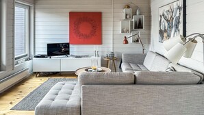 A modern living room with a grey sofa, a television, and a red artwork on the wall. - Awesome apartment in Tjørhom (Tjørhom)