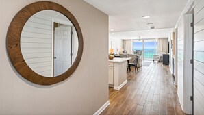 A spacious hallway with a large round mirror, leading to a balcony with a view of the ocean. - Destin Gulfgate 2 Bedroom, 2 Bath Gulf-Front Condo! (Destin)