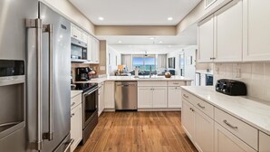 A modern kitchen with stainless steel appliances, white cabinetry, and a view to the outside. - Destin Gulfgate 2 Bedroom, 2 Bath Gulf-Front Condo! (Destin)