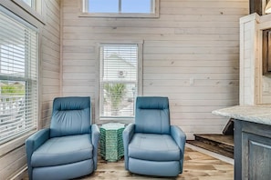 Una habitación con dos sillones de cuero azul, una mesita y un ventanal con persianas.