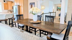 A dining area with a wooden table, chairs, and a vase of flowers. - Luxurious 5BR Inlet View Home with Elevator – South Shore Marina (North Bethany)