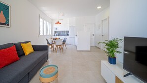 Una sala de estar moderna con un sofá gris, un televisor y un comedor con mesa y sillas.