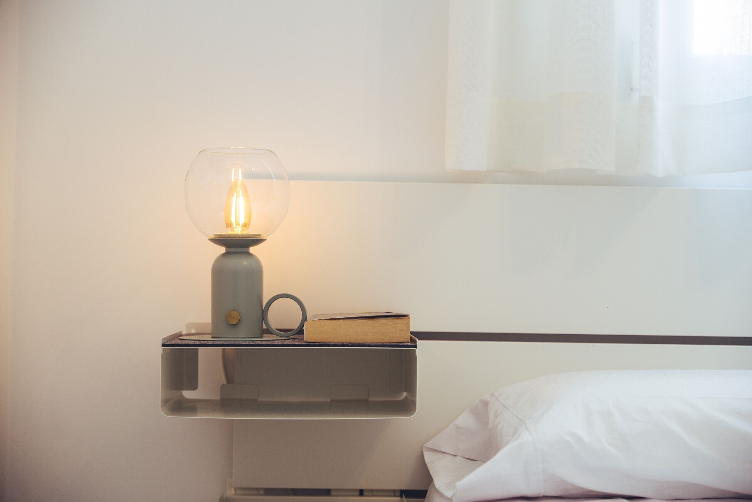 A bedside table with a lamp, a book, and a tissue box.