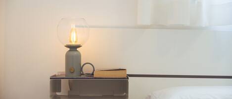 A bedside table with a lamp, a book, and a tissue box.