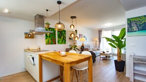 Une cuisine moderne avec une table et des chaises en bois, un four encastré et des luminaires suspendus.