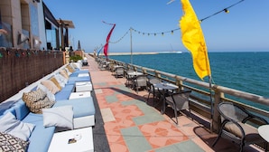 Une terrasse en bord de mer, dotée de sièges et de tables, qui offre une vue sur l’océan.
