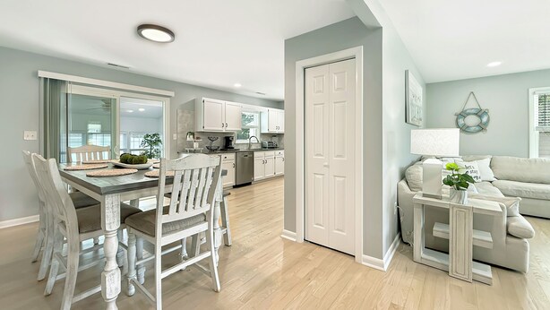 Una cocina moderna con armarios blancos y un comedor con una mesa y sillas de madera.