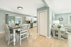 A modern kitchen with white cabinets and a dining area with a wooden table and chairs. - Newly Renovated Rancher Close to Restaurants and Midway Park (Rehoboth Beach)