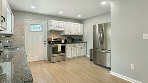 Una cocina moderna con armarios blancos, electrodomésticos de acero inoxidable y suelo de madera.