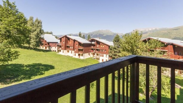 Une vue d’un bâtiment de style chalet, avec une terrasse en bois au premier plan.