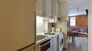Une cuisine compacte équipée d’un évier, d’un four à micro-ondes, d’un four et d’un lave-linge.