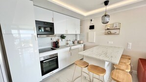 Una cocina moderna con armarios blancos, encimera de mármol y taburetes de madera.