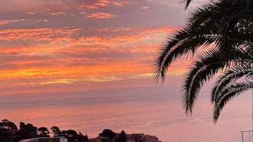 Une piscine à débordement offrant une vue sur le coucher de soleil au-dessus d’un quartier résidentiel.