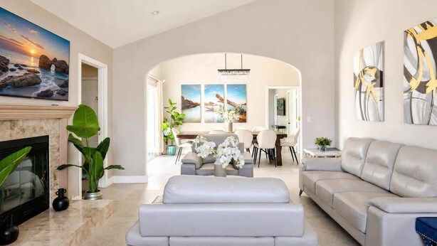 A spacious living room with a fireplace, a dining area, and a modern sofa. - Disneyland/Knott's 6BR, 4BA, 3000 sqft, No Tax (Anaheim)