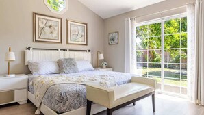 A bedroom with a large bed, bedside tables, a bench, and a view through a large window. - Disneyland/Knott's 6BR, 4BA, 3000 sqft, No Tax (Anaheim)