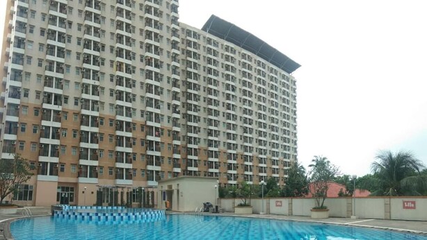 A large swimming pool with a checkered pattern, surrounded by a high-rise building with multiple balconies. - Capital O 93937 Aditya Rooms  (Depok)