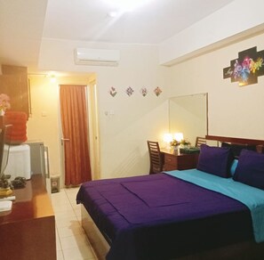 A bedroom with a bed, a desk, a chair, a mirror, and an air conditioning unit. - Capital O 93937 Aditya Rooms  (Depok)