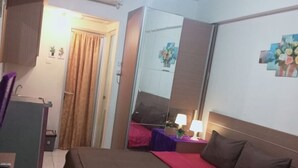 A hotel room with a bed, a desk, a mirror, and a window with curtains. - Capital O 93937 Aditya Rooms  (Depok)