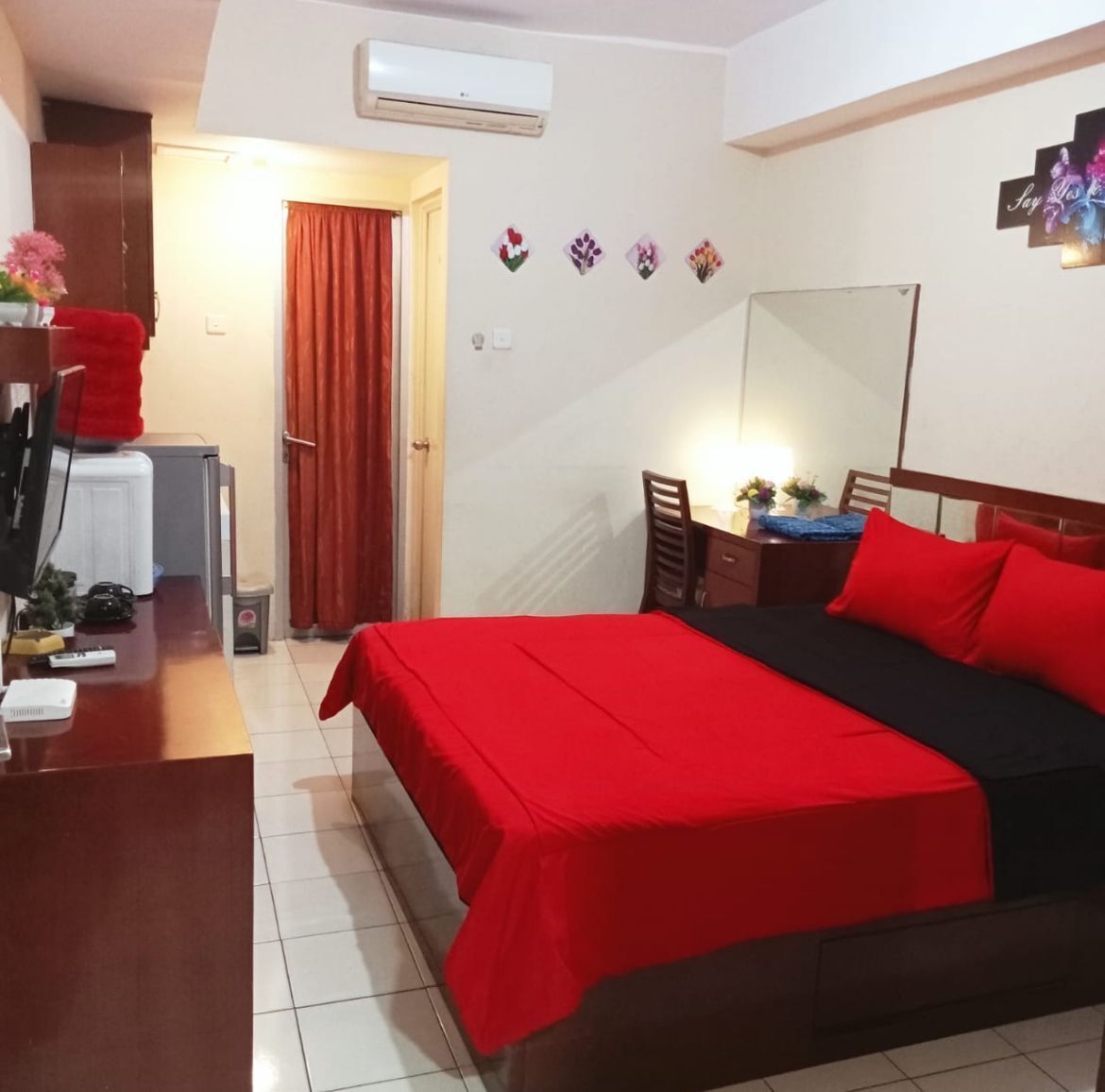 Een hotelkamer met een bed, een bureau, een stoel, een spiegel en een airconditioning.