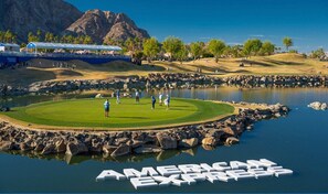 Un parcours de golf avec un étang et les mots « AMERICAN EXPRESS » inscrits sur la surface de l’eau.