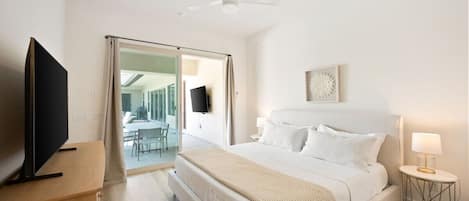 Ein Hotelzimmer mit einem Bett, einem Fernseher, einem Deckenventilator, einem Nachttisch mit Lampe und Blick ins Freie.
