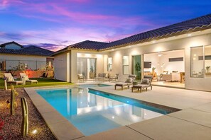A modern house with a swimming pool, outdoor furniture, and a patio area.
