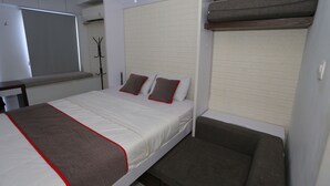 A bedroom with a bed, a bench, a wardrobe, and a window. - Collection O 93914 Iconic Residence  (Bekasi)