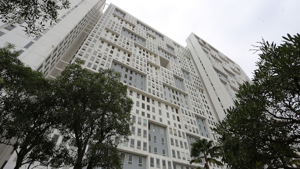 A high-rise building with a grid-like facade, surrounded by trees. - Collection O 93914 Iconic Residence  (Bekasi)