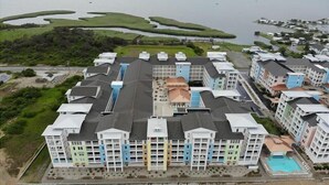 A multi-story hotel with a central courtyard, surrounded by a golf course and a beach. - Book Lazy Waves 414B | Sandbridge Vacation Condo (Virginia Beach)
