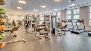 A gym with various exercise equipment, including treadmills and weight machines. - Book Lazy Waves 414B | Sandbridge Vacation Condo (Virginia Beach)
