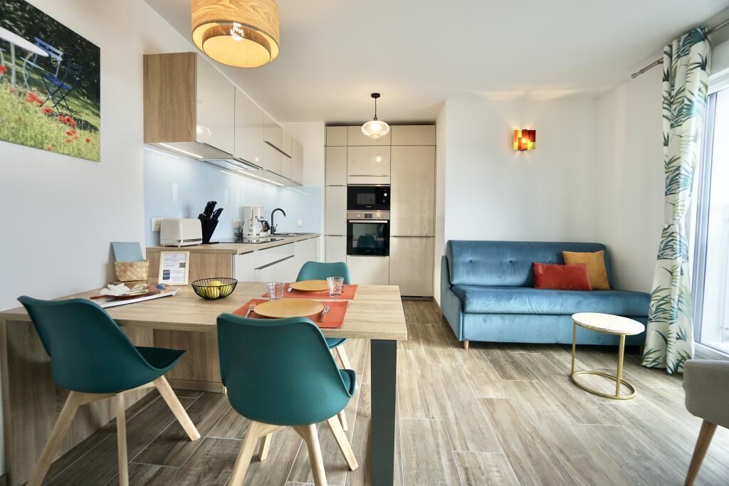 Una cocina moderna con zona de comedor, un sofá azul y una pequeña mesa.