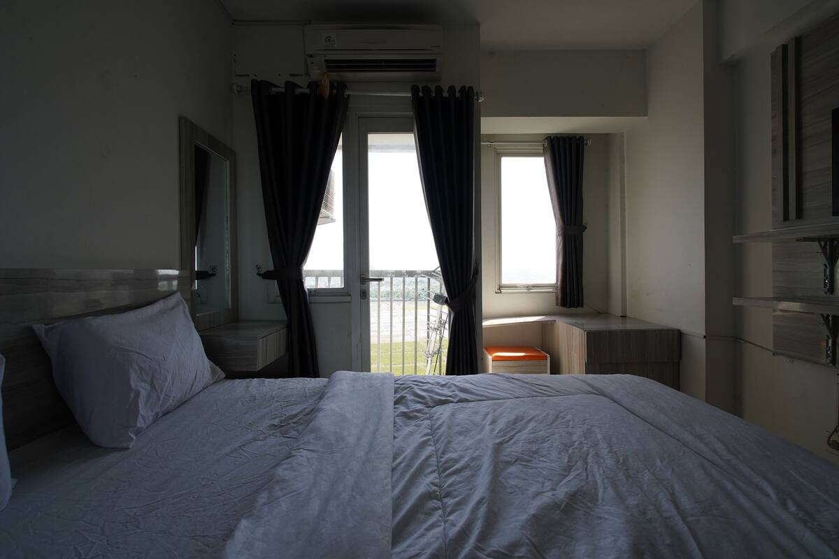 Ein Hotelzimmer mit Bett, Schreibtisch, Stuhl und einem Fenster mit Vorhängen.