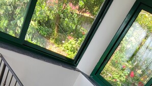 A staircase with a metal railing leading to a landing. There are large windows on the landing, offering a view of greenery outside. - Camera immersa nel verde (Sorrento)