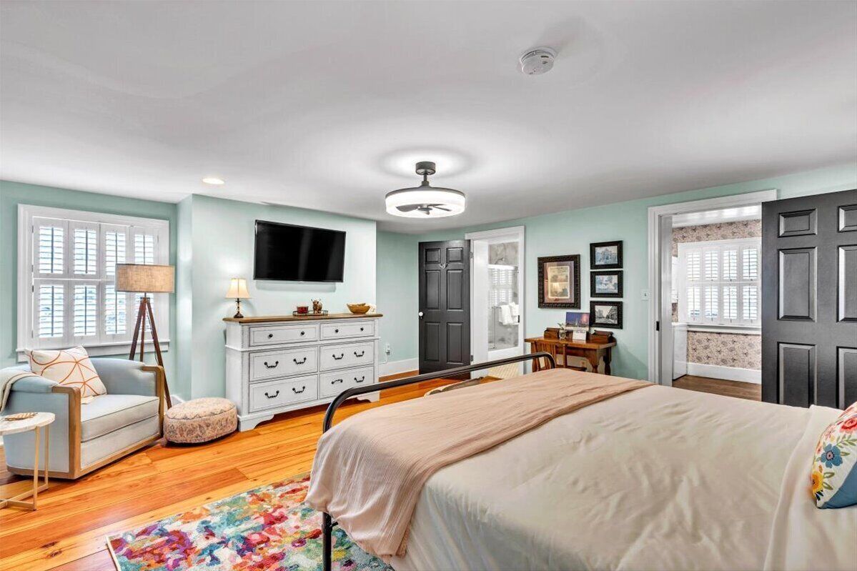 A bedroom with a bed, dresser, and a television on the wall.