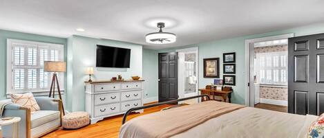 A bedroom with a bed, dresser, and a television on the wall.